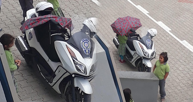 Kırık şemsiyesiyle polisin motosikletini yağmurdan korudu